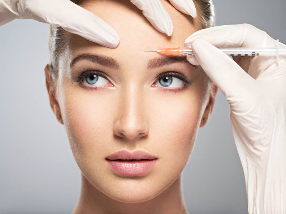 Woman getting cosmetic botox injection in forehead
